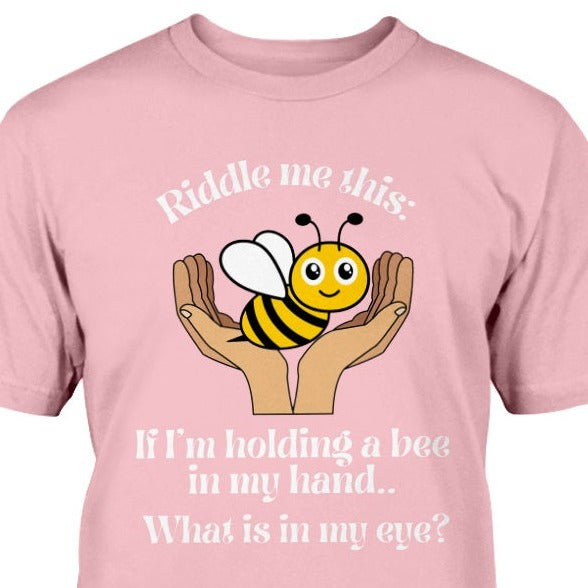 t-shirt with a hand holding a bee and text says Riddle me this: If I'm holding a bee in my hand.. What is in my eye?